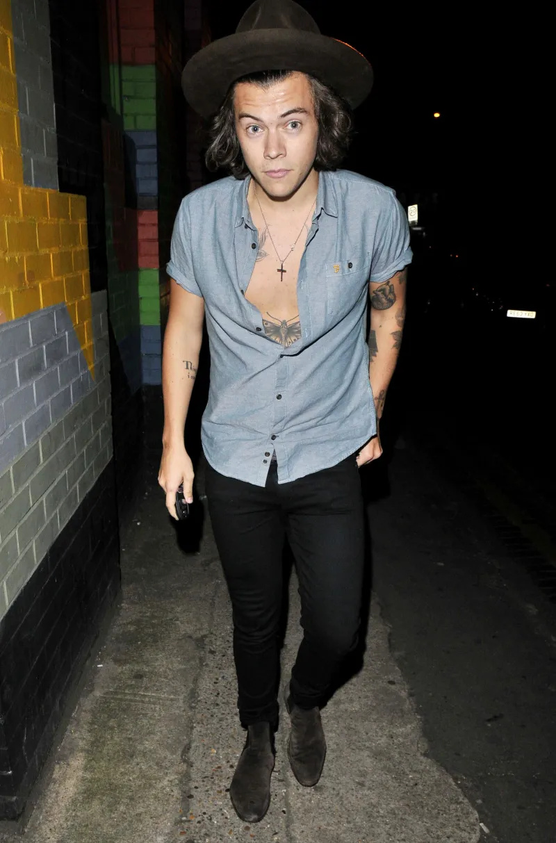   Harry Styles kõndis õues, seljas sinine nööbitav särk ja pruun müts